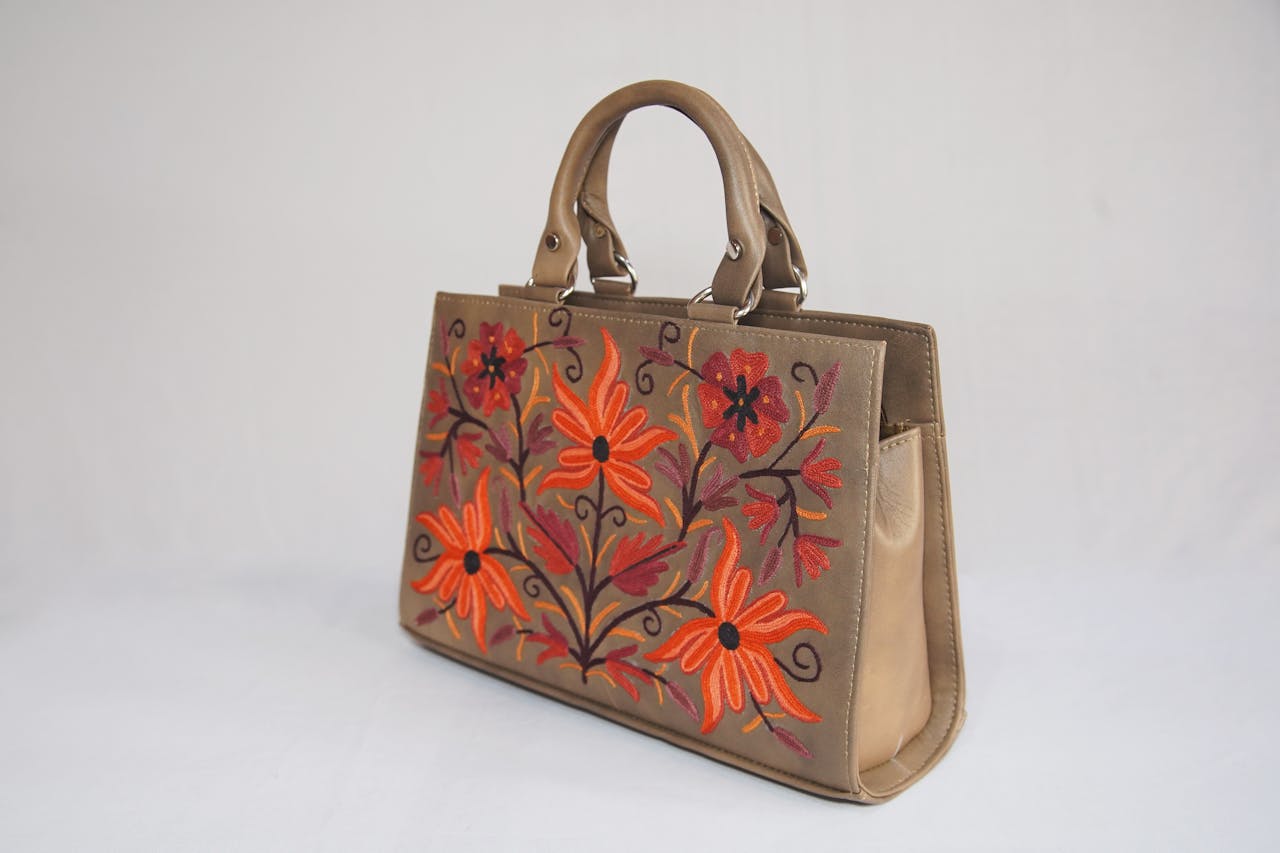 Stylish handbag with vibrant floral embroidery on a white background, perfect for fashion shoots.